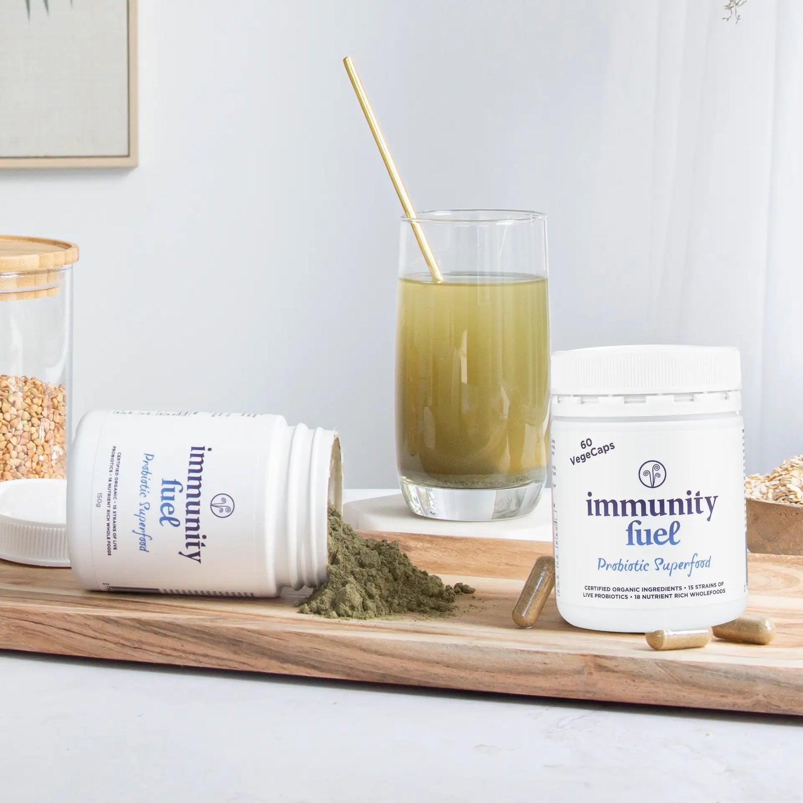 Two containers labeled 'immunity fuel' on a wooden tray with a glass of green juice and a spoon.